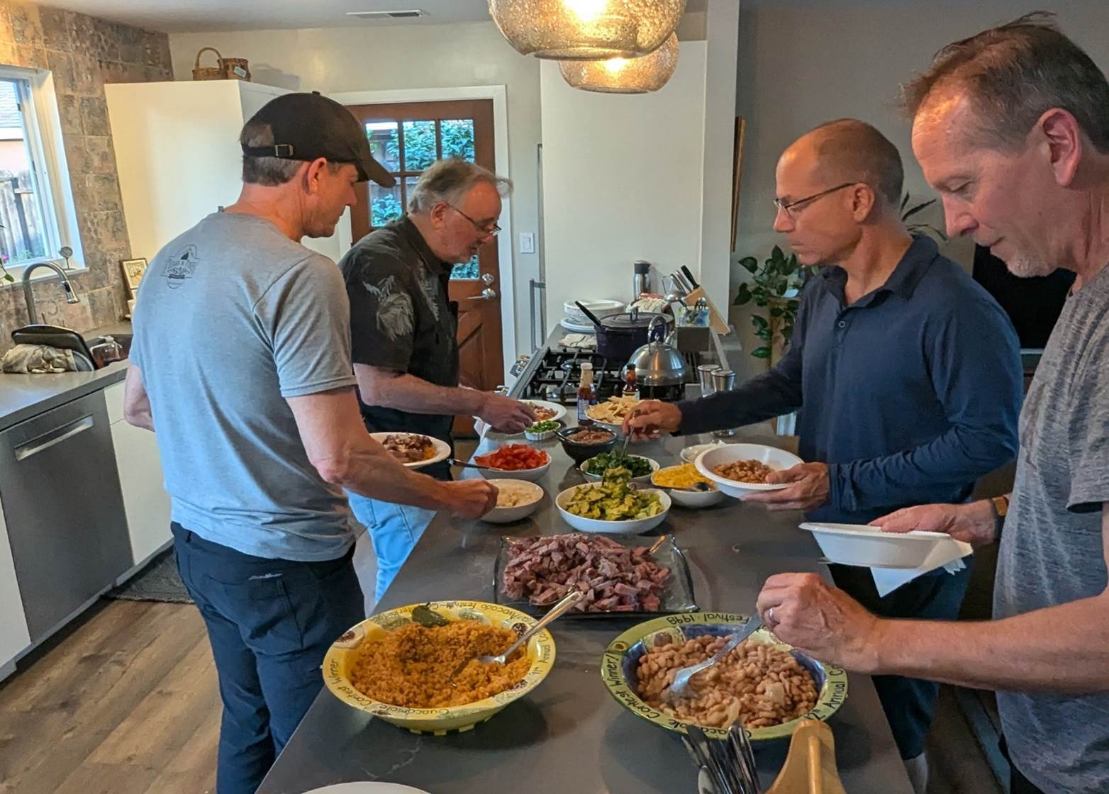 A group of men standing around a table full of food

Description automatically generated